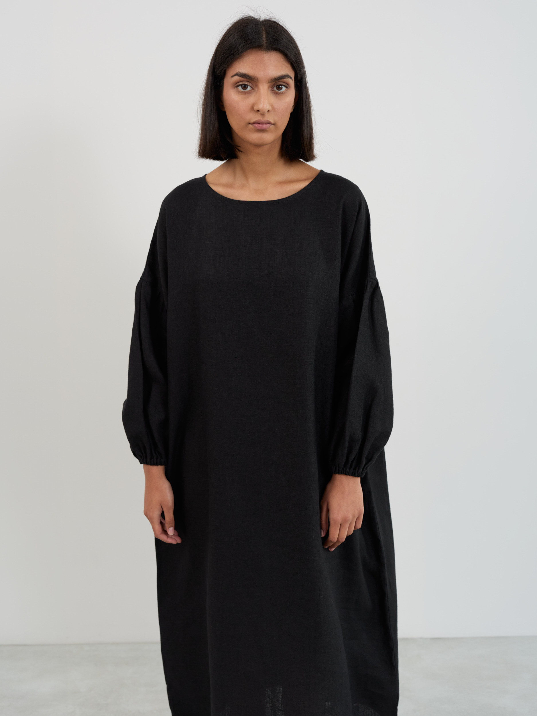Front close-up of the Briar black linen midi dress showing wide boat neckline and balloon sleeve volume with elastic gathered cuffs