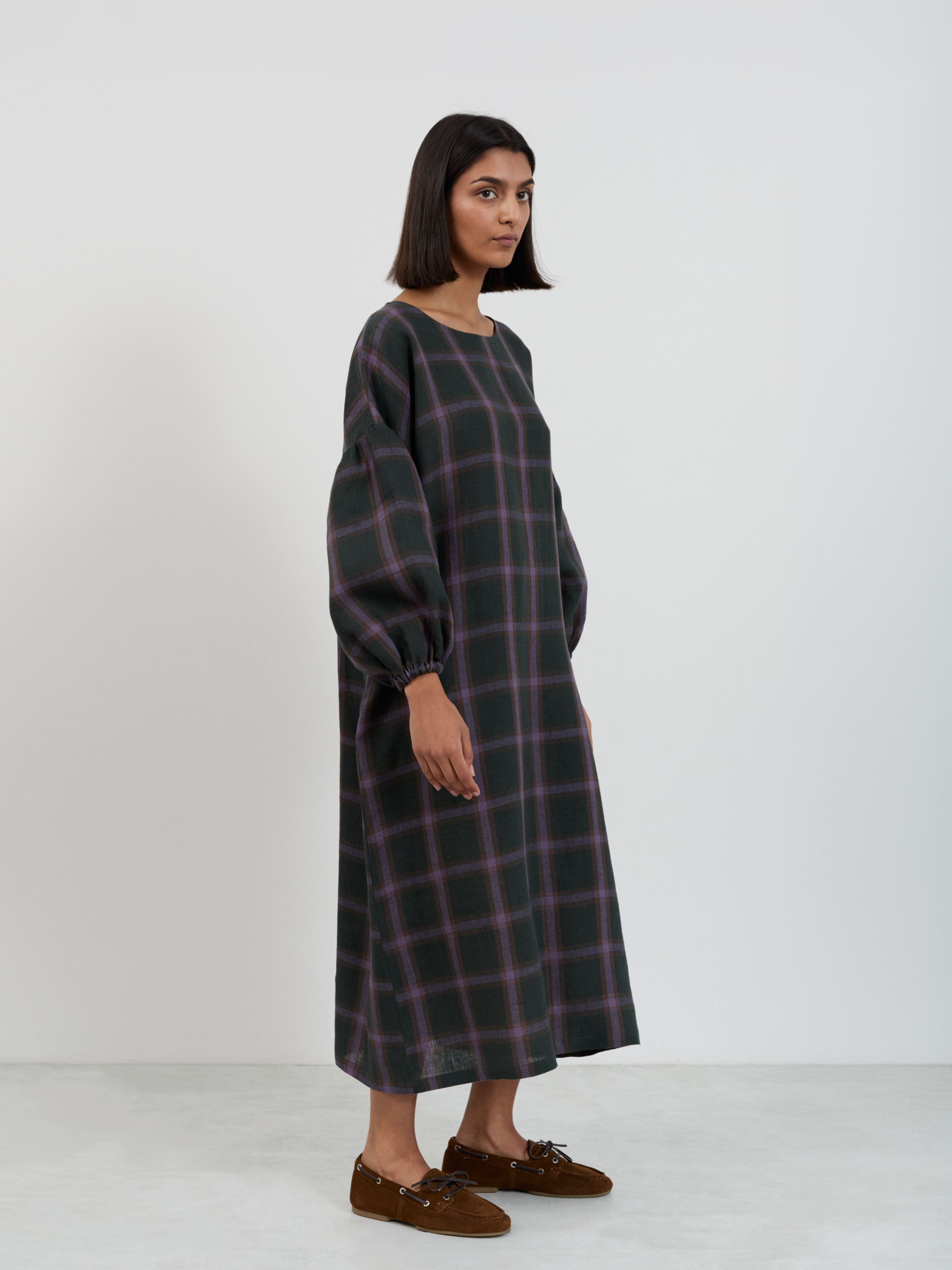 Three-quarter side view of the Briar linen midi dress in purple plaid windowpane pattern showing balloon sleeves and mid-calf length