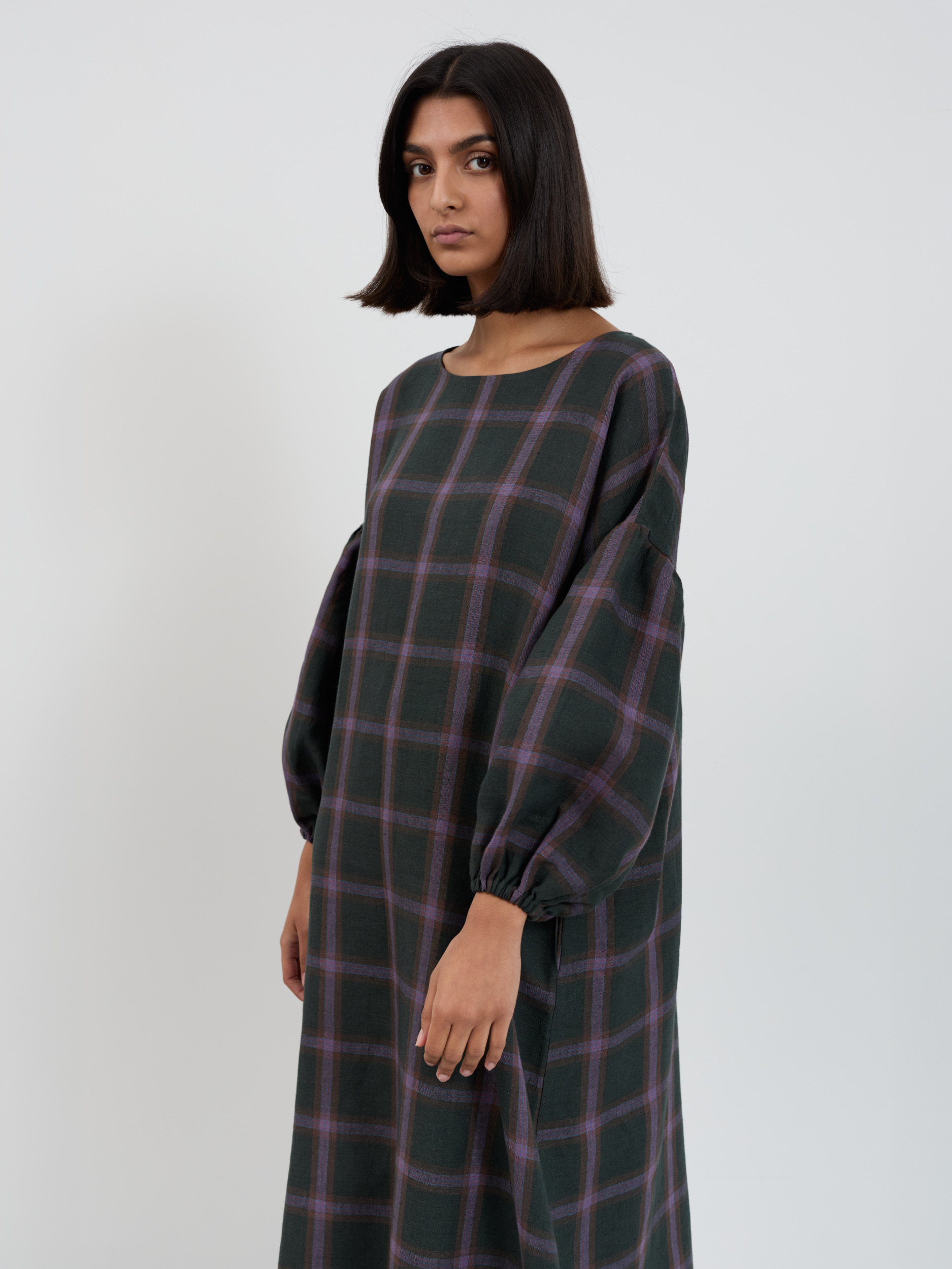 Close-up front view of the Briar purple plaid linen dress showing boat neckline, drop-shoulder construction, and elastic-cuff balloon sleeves