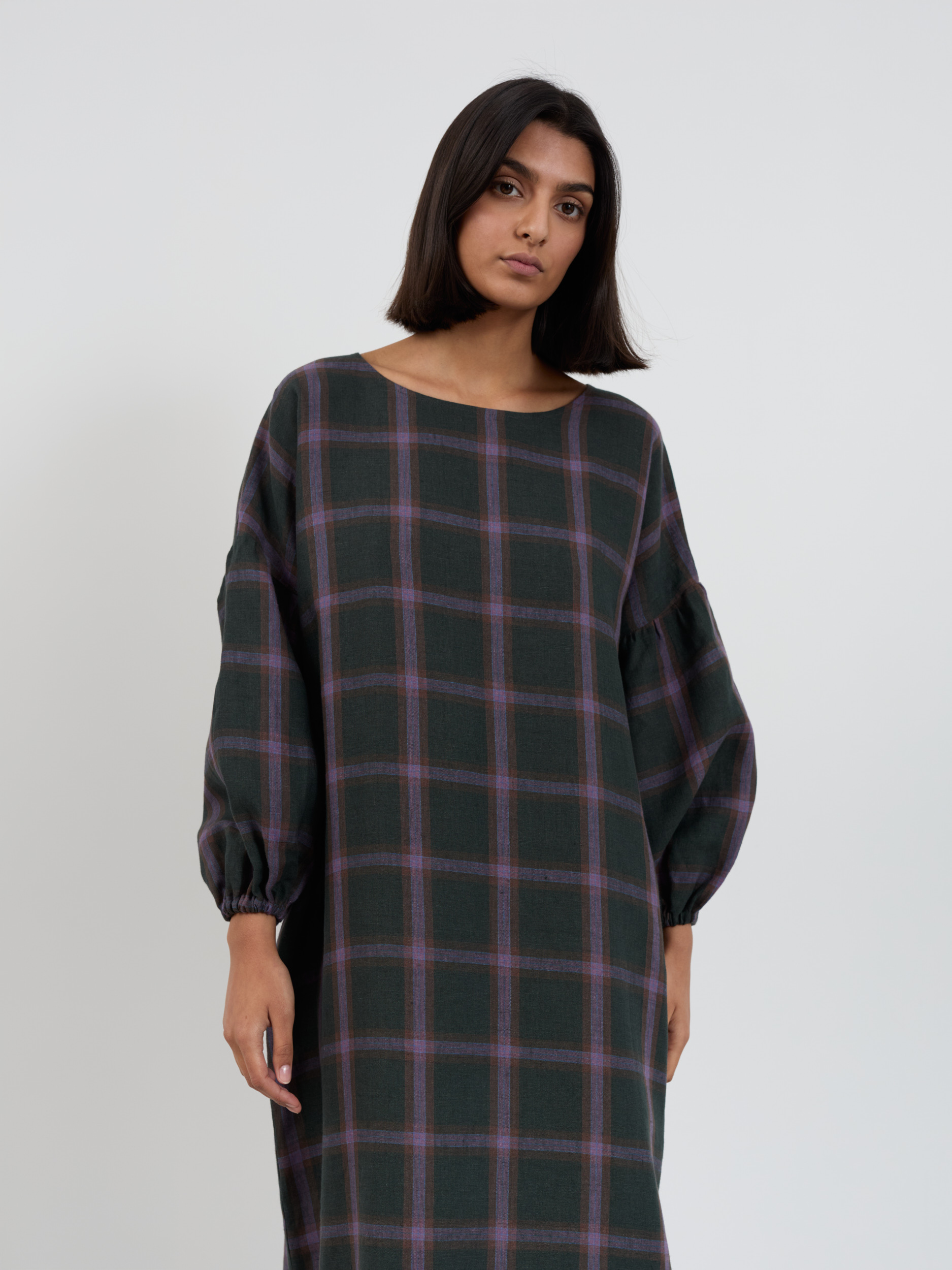 Side-back view of the Briar linen midi dress in purple plaid showing relaxed straight silhouette and balloon sleeve volume