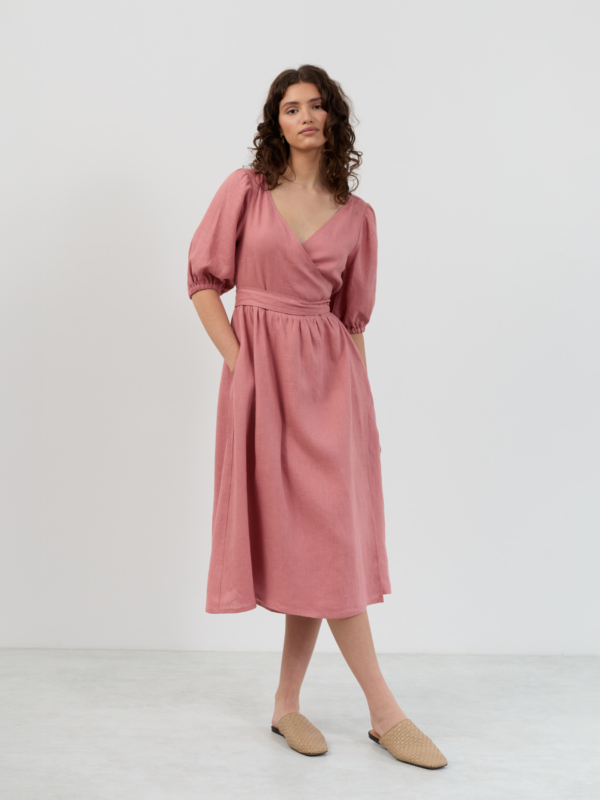Front angled view of salmon pink linen midi wrap dress with puff sleeves, side seam pocket and fit-and-flare shape
