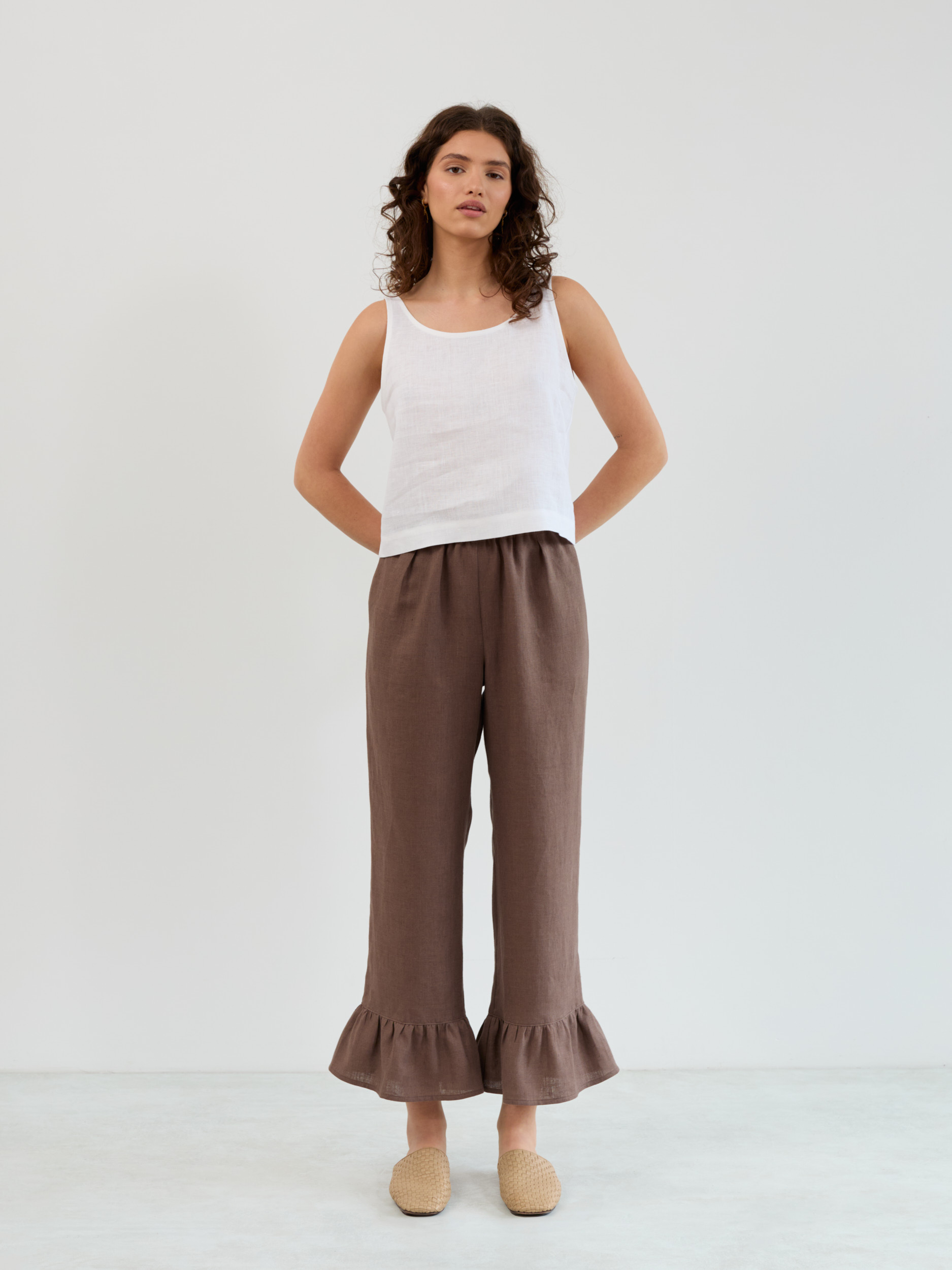 Front standing view of the Gigi cocoa linen pants showing the straight relaxed fit and ruffle bottom detail